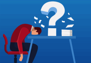 cartoon man with head on desk where a giant question mark sits