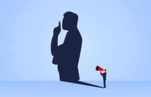 the shadow of the speaker who took the loudspeaker holding his hand to his lips in a hush sign